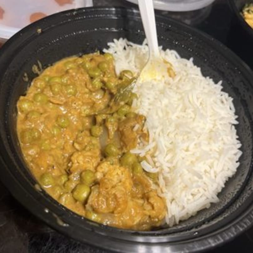 AniKri Foods' Indian chicken curry with peas and white rice in a black bowl.
